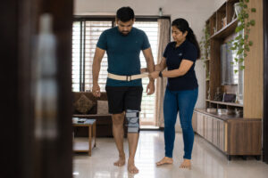 Physiotherapist supporting patient with guided walking exercise after knee surgery
